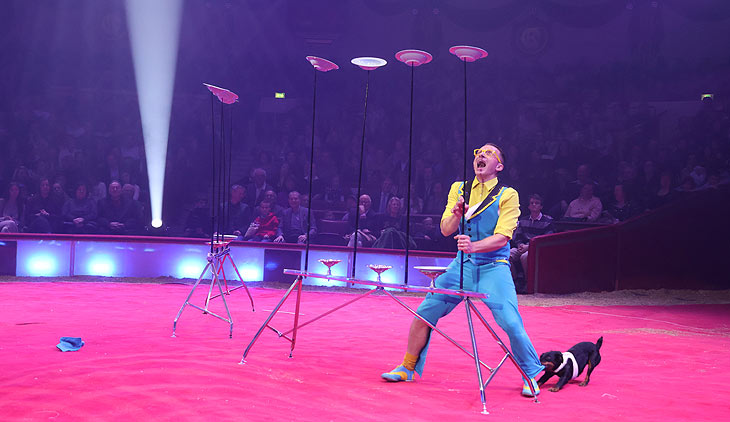 Liviu Tudor mit Tellern und Hund: Circus Krone Winterspielzeit 2024: „Farbenspiel“ ist der Programmtitel der Wintersaison bis 07.04.2024. Premiere am 25.12.2023 (©Foto: Martin Schmitz)